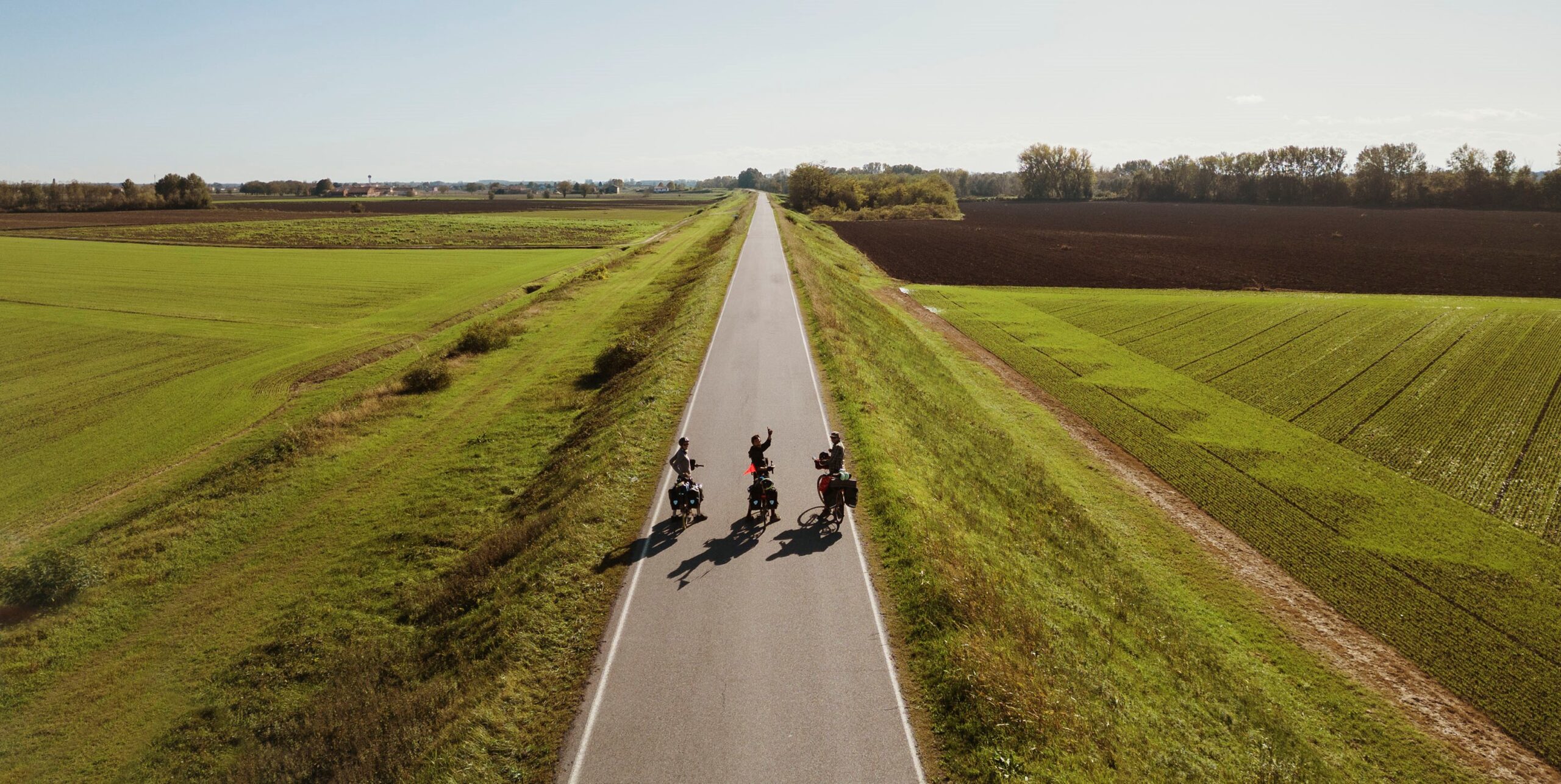 Cyclistes sur la route entourés de nature et de champs verts