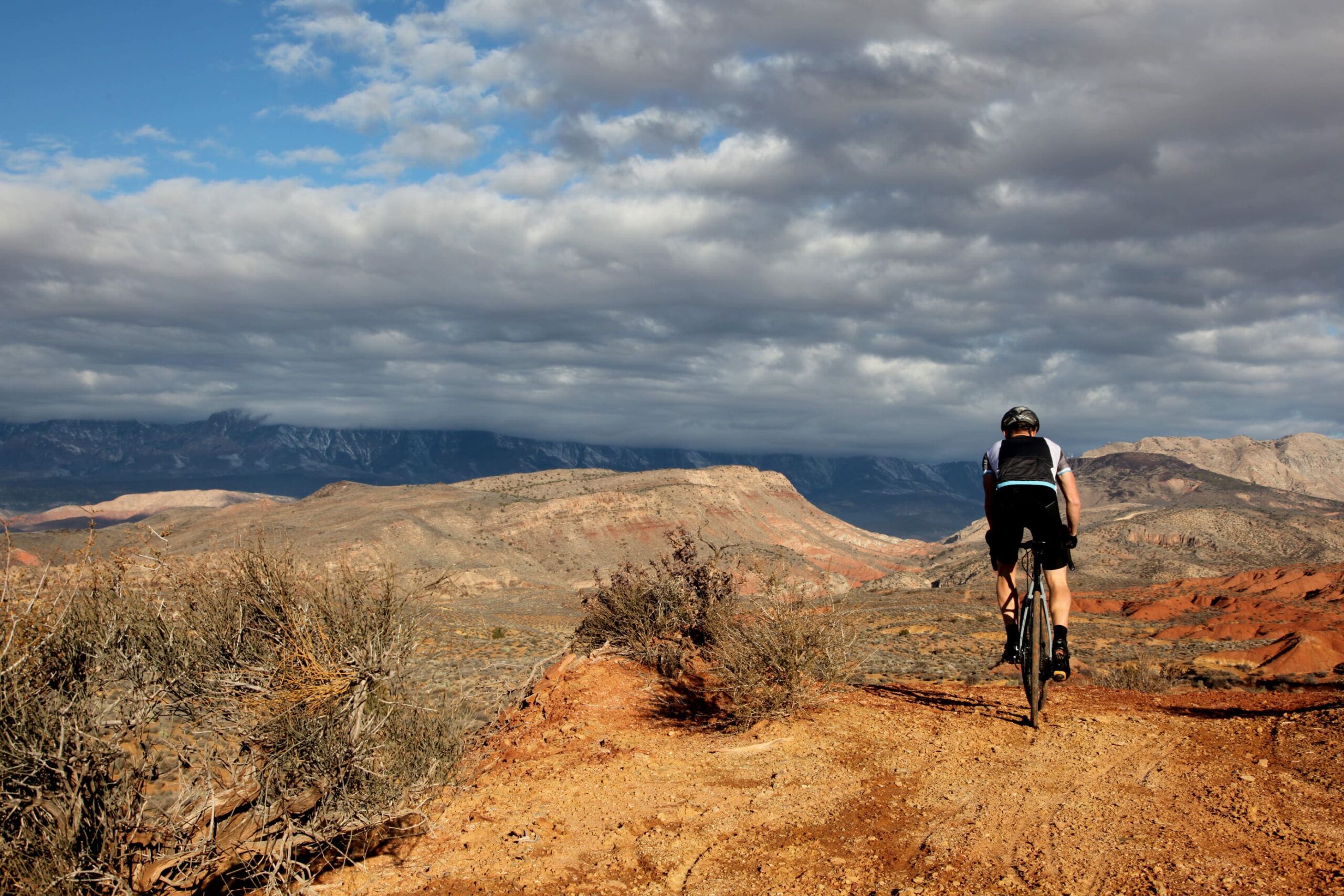 Fietser bovenop een badland. Het woestijnlandschap is te zien vanaf zijn fiets.