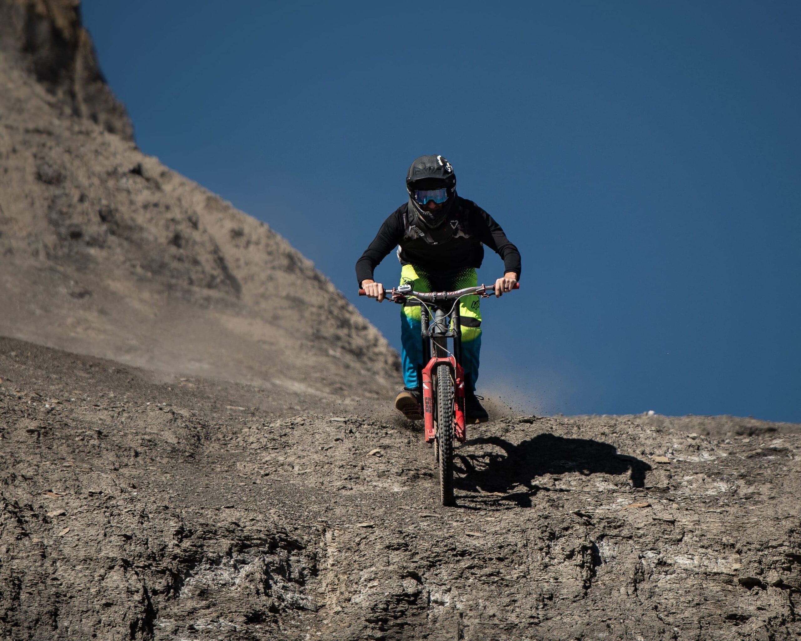 Ciclista de MTB bajando por desierto de piedras oscuras.