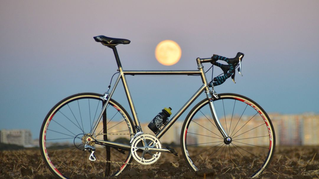 Bici con neumáticos sólidos antipinchazos de Tannus Tires en el campo con un anochecer en la ciudad de fondo.