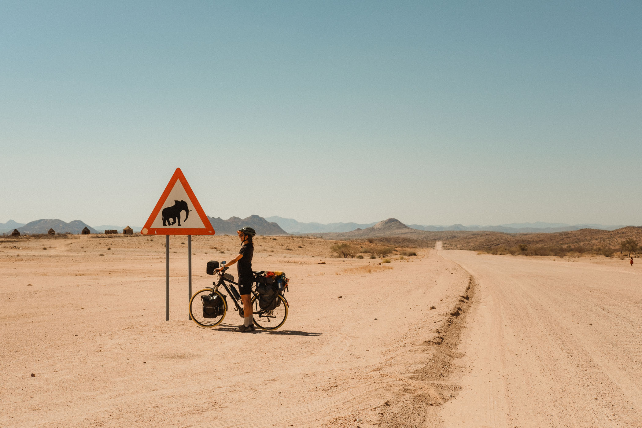 Elena d eKaraban with her bike next to an "Elephant Danger" sign.