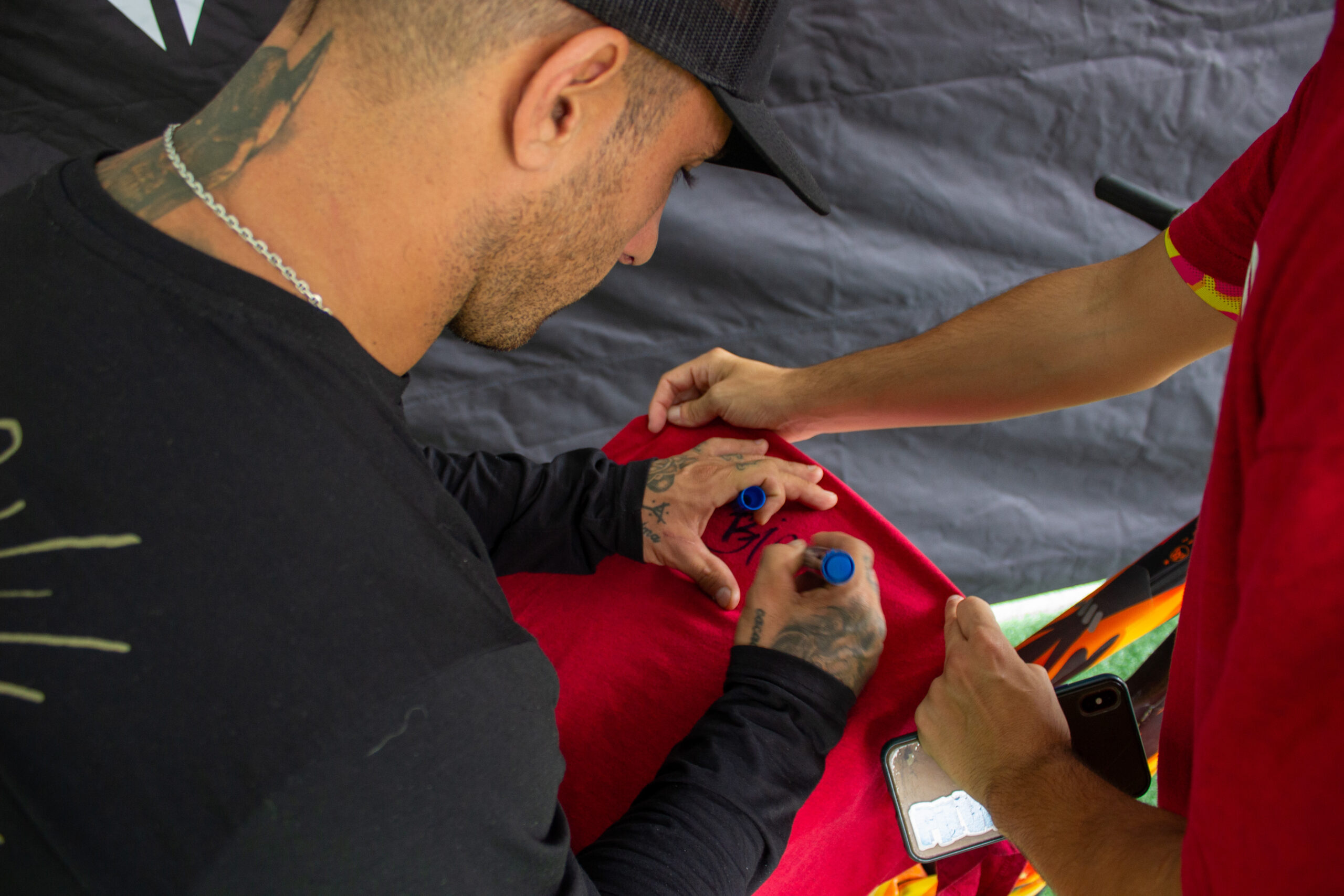 Bienvenido Aguado signeert een T-shirt bij de Tannus-stand op Sea Otter 2024.