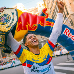 Juanfer Velez mit dem Gürtel des Red Bull CerroAbajo DH Urban Champion, der mit offenen Armen in den Himmel schaut und feiert.